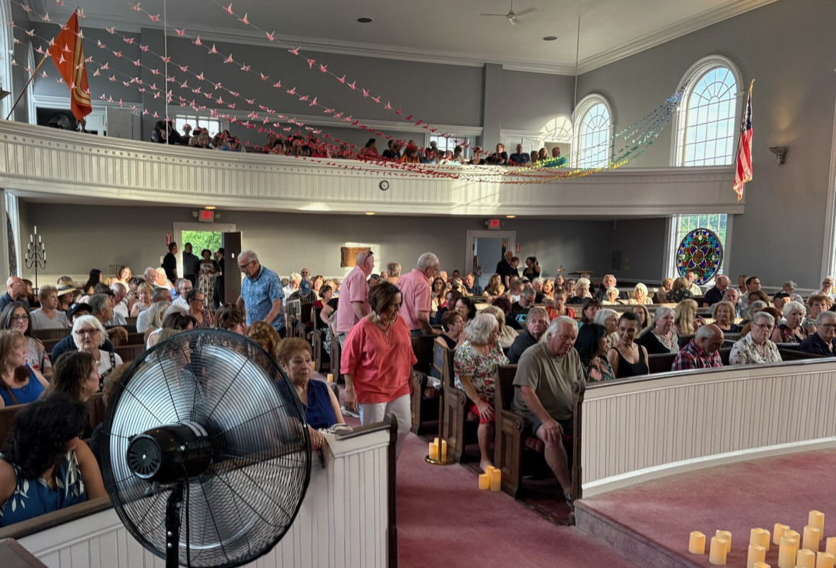 An audience of mostly people over 50 sit inside the sanctuay main floor while several people overlook the main seating area via balcony seats.  Approximately 400 people may be seated there.